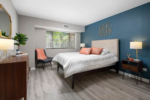 A bedroom with a bed, chair, and a plant.