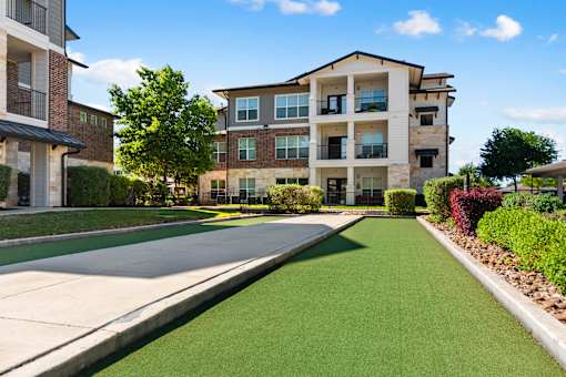 A sunny day at a residential area with apartment buildings and a green lawn.