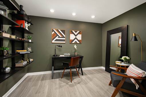 A room with a desk, chair, and shelves.