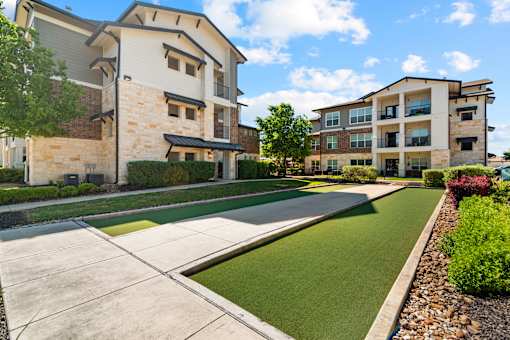 A modern apartment complex with a well-maintained lawn and landscaping.