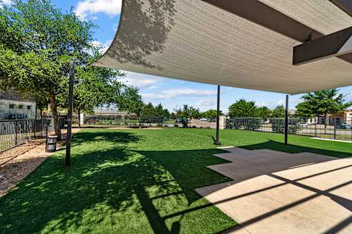 A park with a grassy area and a shaded walkway.