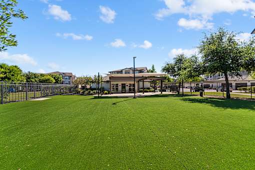 A large, well-maintained grassy field with a building in the background.