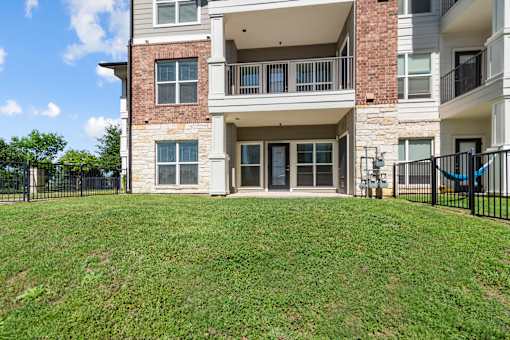 A large grassy area in front of a two-story apartment building.