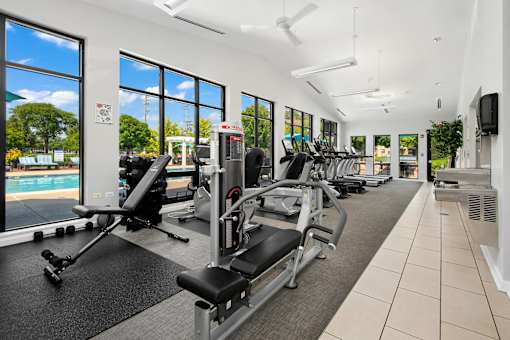 A gym with a row of treadmills and exercise machines.