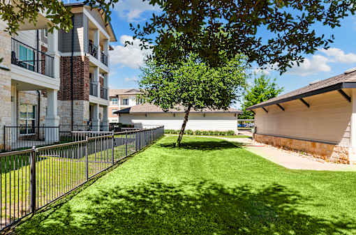 A tree in a grassy area in front of a building.