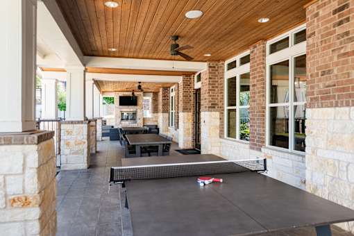 A ping pong table is in the middle of a covered patio.