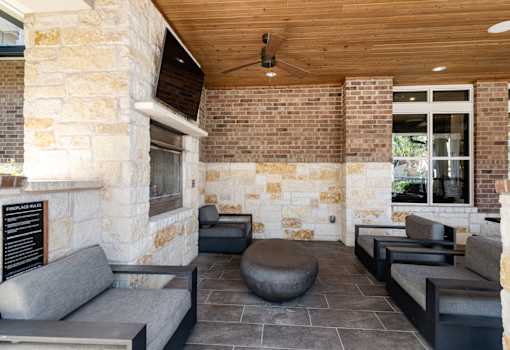 A modern outdoor seating area with a stone wall and wooden ceiling.