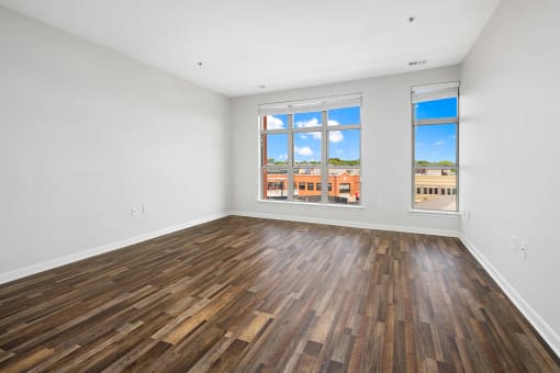 an empty living room with wood floors and a window at The Bayshore Place Apartments in Glendale, WI