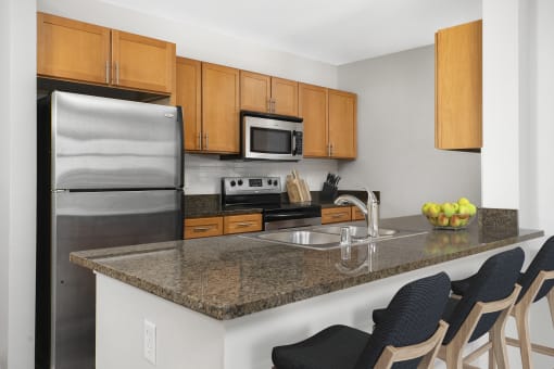 a kitchen with a granite counter top and stainless steel appliances at The Bayshore Place Apartments in Glendale, WI
