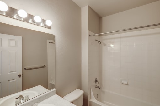 a bathroom with a white tub and a sink and a mirror