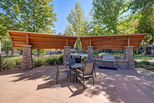 A patio with a table and chairs under a wooden pergola.