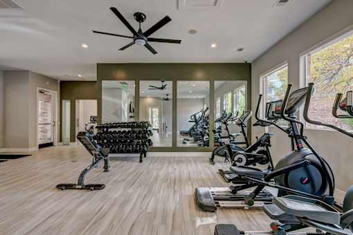 a gym with cardio machines and a ceiling fan