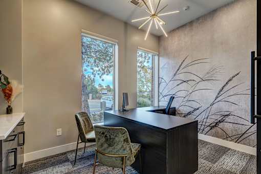 a home office with a large window and a desk with chairs