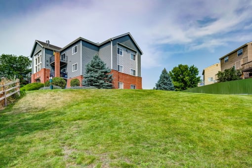 the backyard of a house on a hill with green grass