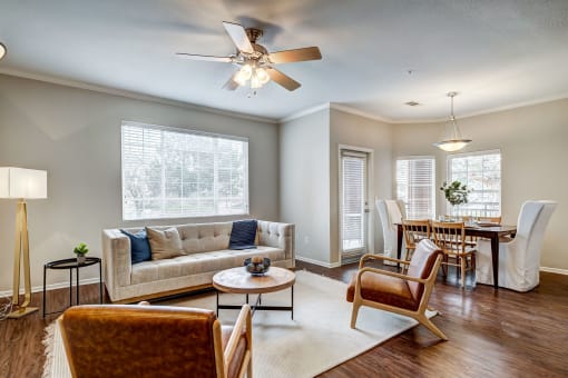 Aurora, CO Apartments For Rent - Sonoma Resort At Saddle Rock - Living Room With Couch, Wood-Style Flooring, Coffee Table, Two Chairs, Floor Lamp, Area Rug, Ceiling Fan, And Windows.