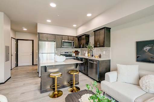 A modern kitchen with a white couch and bar stools.