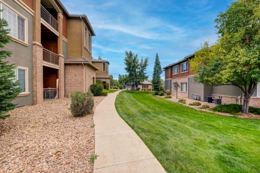 a walkway between two apartment buildings with grass and trees