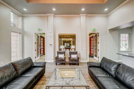 a living room with leather couches and a glass coffee table