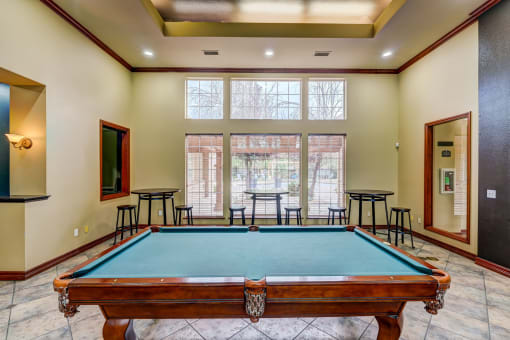 a pool table in the corner of a room with a large window