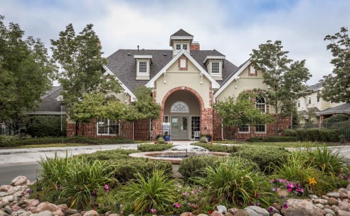 the front of a house with a fountain and gardens