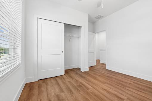 A room with a white door and wooden flooring.