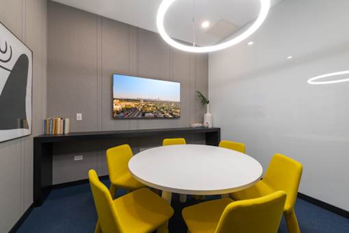 A conference room with a white table and yellow chairs.