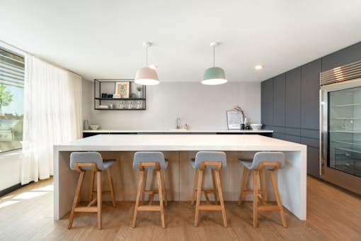 A kitchen with a white countertop and wooden bar stools.