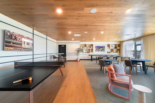 A ping pong table is in the middle of a room with a couch and chairs.