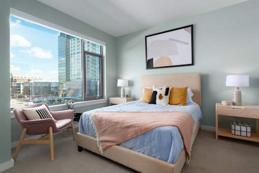A bedroom with a large bed and a chair by the window.