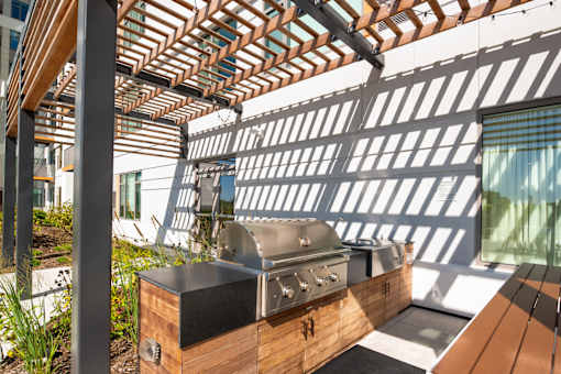 A modern outdoor kitchen with a grill and a pergola.