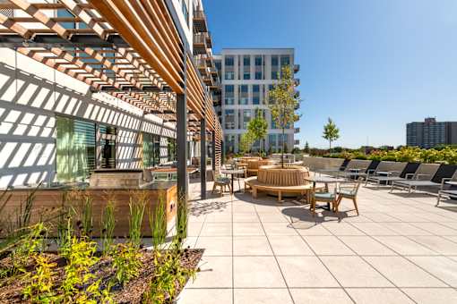 A modern outdoor seating area with wooden furniture and a wooden pergola.