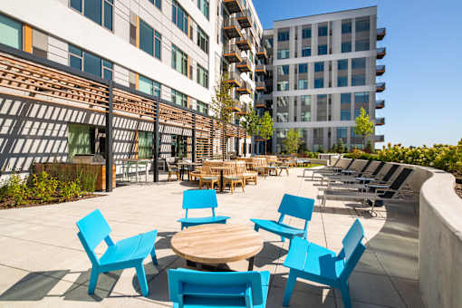 A patio with blue chairs and tables in front of a building.