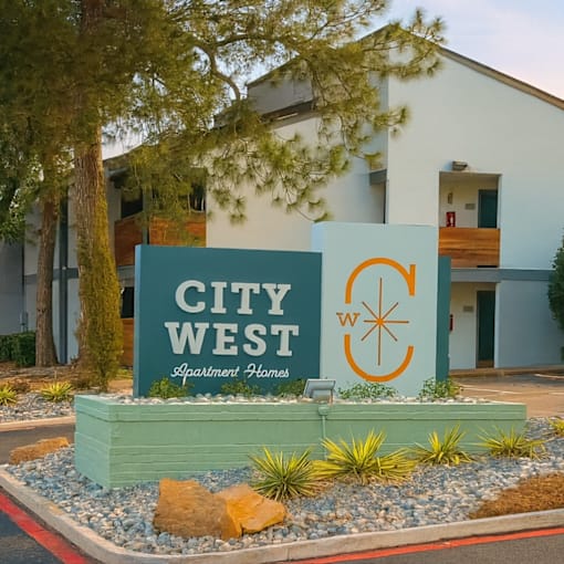A sign for City West Apartment Homes is displayed in front of a building.
