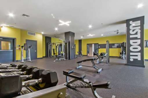A gym with a variety of equipment including dumbbells and weight machines.
