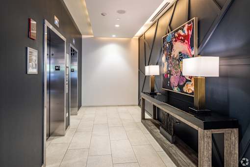 A hallway with a large painting on the wall and a bench.
