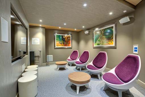 A row of purple chairs are lined up in a waiting room.