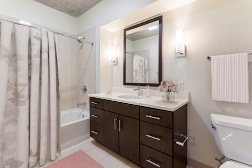 A bathroom with a white tub, a sink with a mirror, and a shower with a curtain.