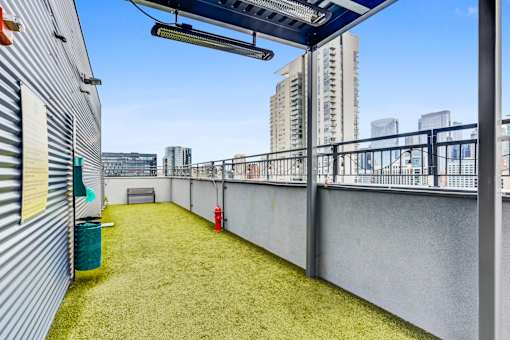 A small patch of grass is surrounded by a metal fence and a building.