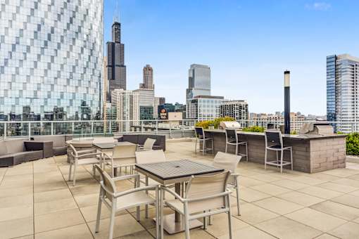 A patio with a table and chairs overlooking a city skyline.