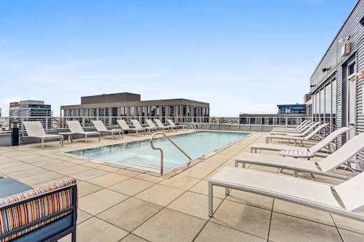 A pool area with sun loungers and a building in the background.