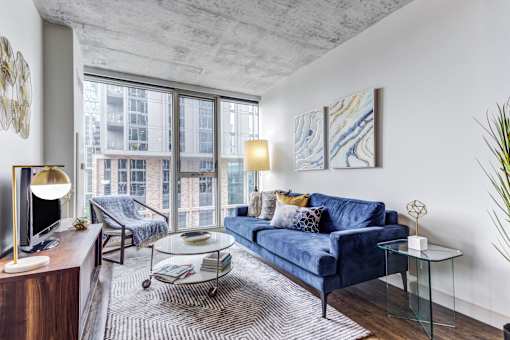 A living room with a blue couch and a glass coffee table.
