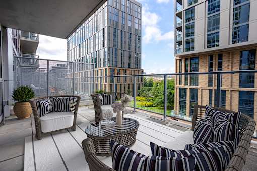 A patio with striped chairs and a table with a vase on it.
