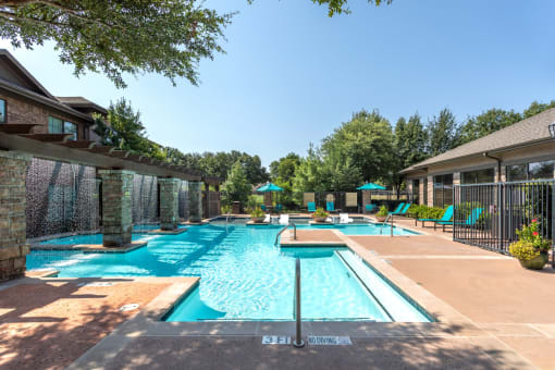 a swimming pool with chairs and umbrellas in front of a house