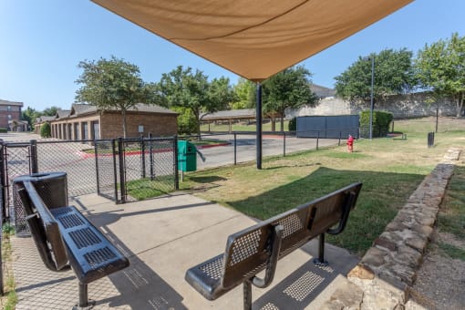 a park with benches and a fence and a tennis court