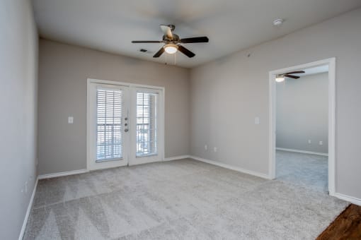 an empty living room with a ceiling fan and window