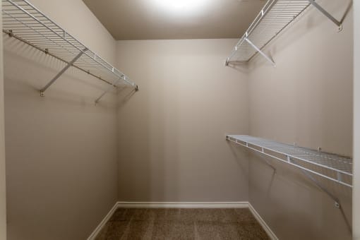 a spacious walk in closet with two shelves and a mirrored wall with two hanging racks