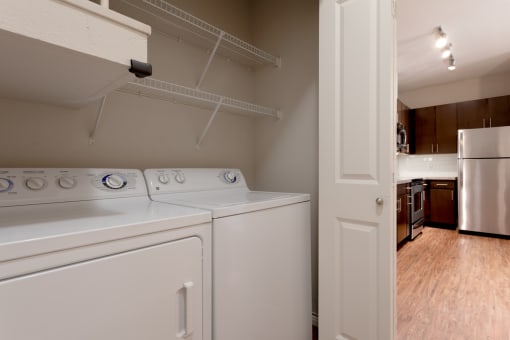 an empty laundry room with a white washer and dryer and a white refrigerator