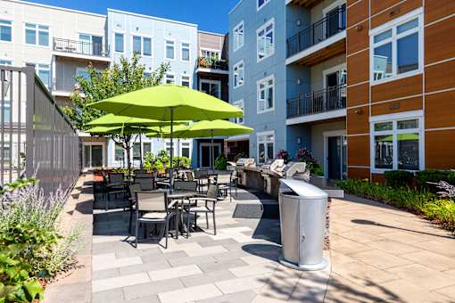 A patio with a table and chairs and a green umbrella.