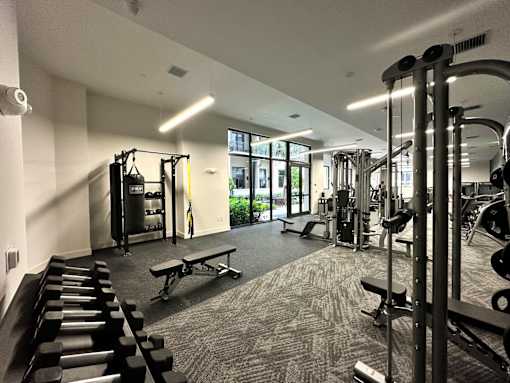 A gym with a variety of equipment including dumbbells, weight machines, and a bench.