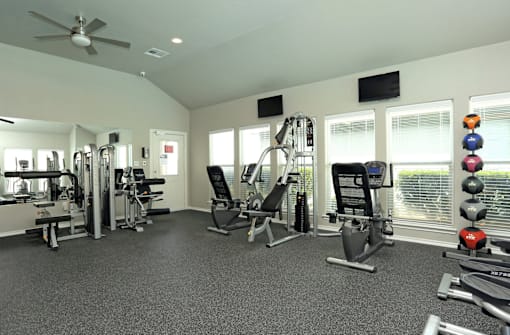 A spacious gym with a variety of equipment including a treadmill, a stationary bike, a rowing machine, a bench press, a squat rack, a leg press machine, a cable machine, a d
